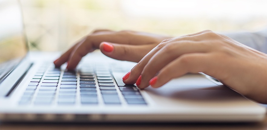 Close-up of female hands typing on laptop keyboard