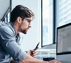 Businessman looking at computer monitor while working in office.