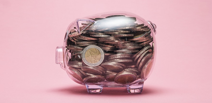 Closeup from transparent piggy bank with two euro coins on pink background. ideal for websites and magazines layouts