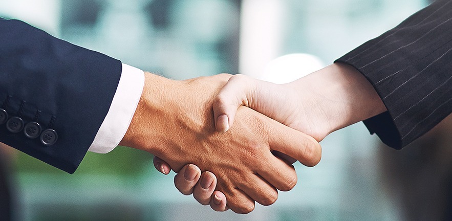 Cropped shot of a businessman and businesswoman shaking hands in a modern office