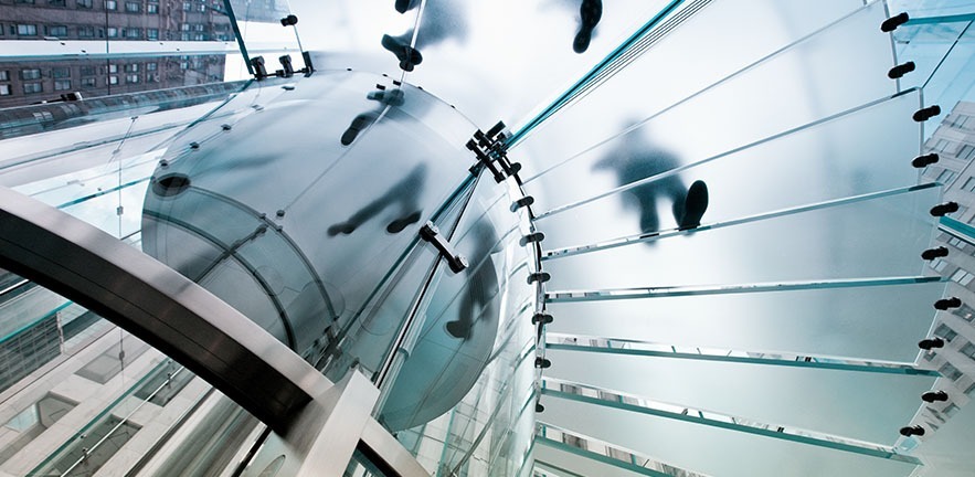 Glass staircase from below with shadows of people walking.