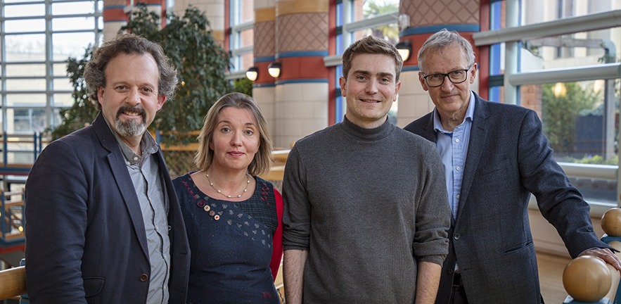 Dr Chris Coleridge, Belinda Bell, Dr Thomas Roulet and Michael Kitson standing in an open walkway in thr Addenbrookes building, Cambridge Judge Business School.