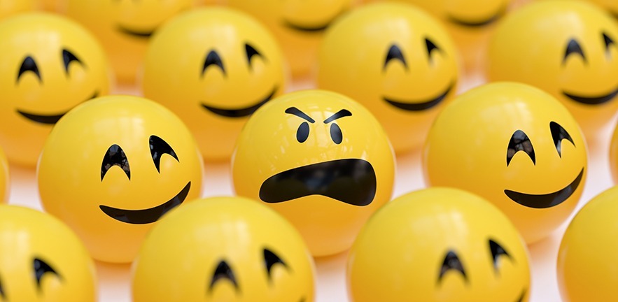 An angry emoji in the midst of smiling emojis.