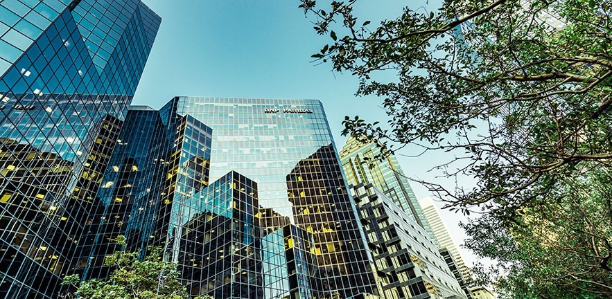 Glass office buildings among green trees.