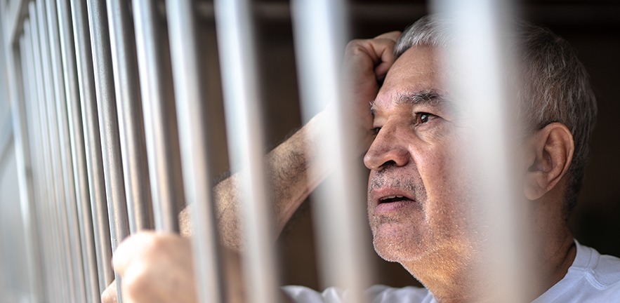 Worries prisoner looking through bars.