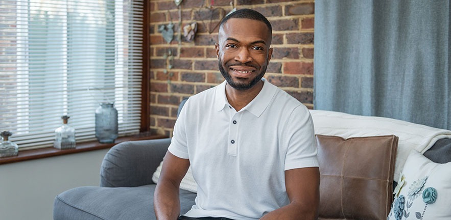 Ken Okoroafor (EMBA 2014) seated on a sofa.