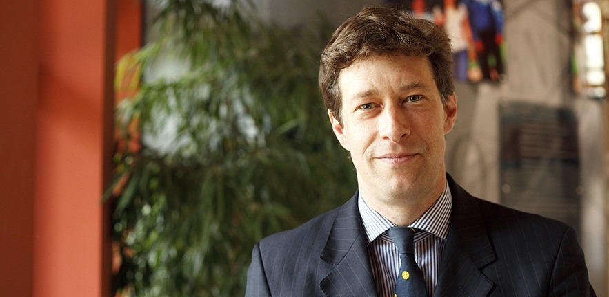 Photograph of Simon Learmount with green plants and terracotta in the background.