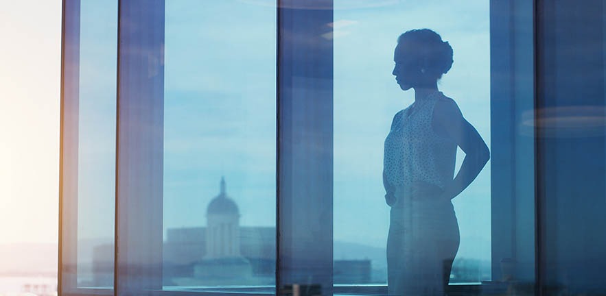 Shot of a businesswoman looking thoughtful while looking out a window.