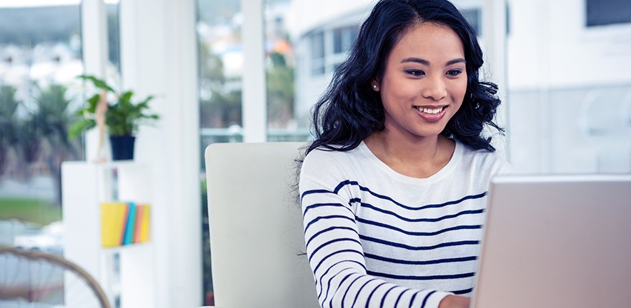 Smiling woman using laptop.