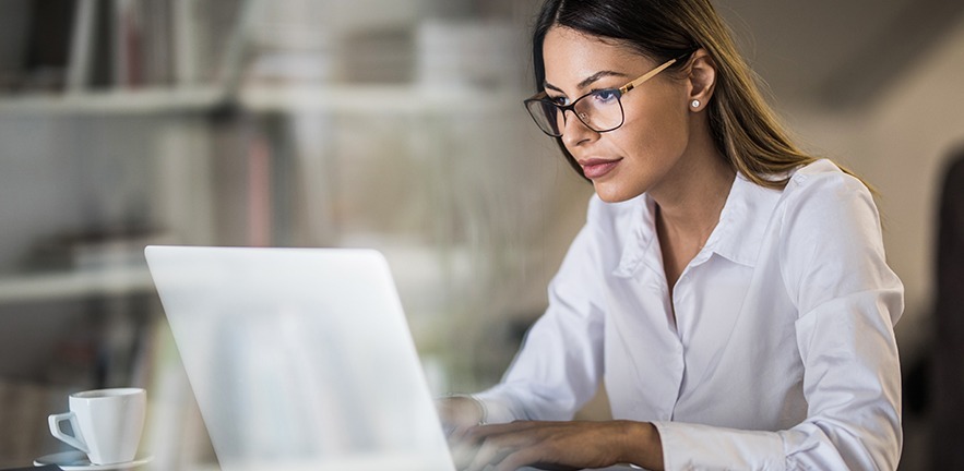 Young businesswoman typing on laptop in office.