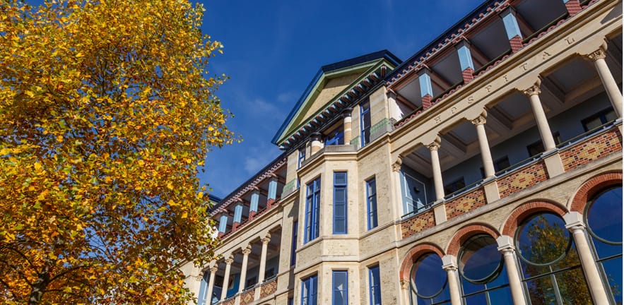 Cambridge Judge Business School with autumnal yellow leaves.