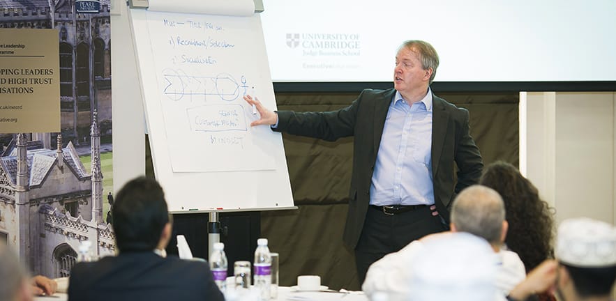 Dr Philip Stiles gestures to brainstorming notes on a flipchart.