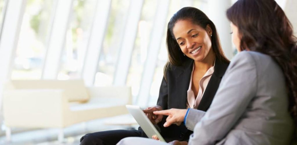 Two people at a career session looking at a tablet smiling while discussing progress.