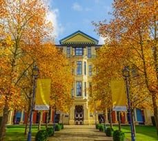 Cambridge Judge Business School with autumnal orange leaves.