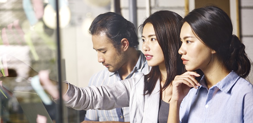 Two Chinese businesswomen and their male colleague in an office.