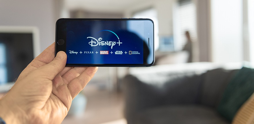 Someone holding up their mobile phone ready to stream Disney +.