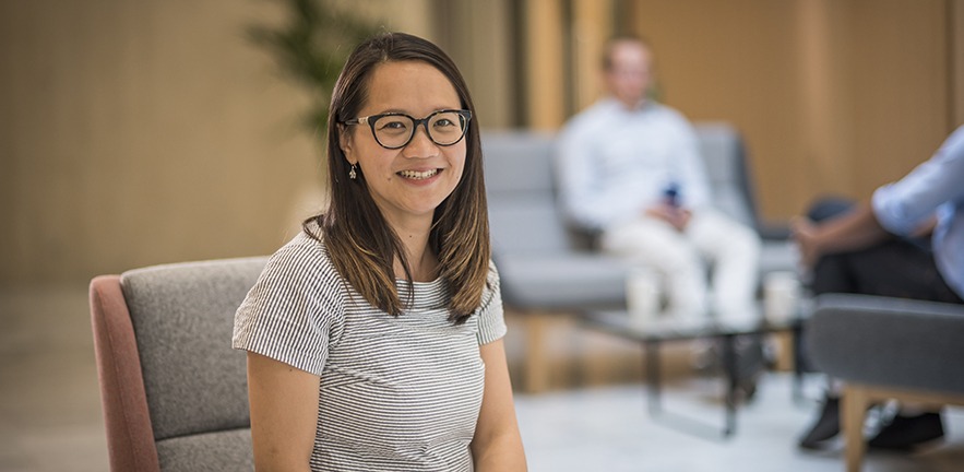 MBA student in focus staring and smiling right at the camera, background is out of focus.