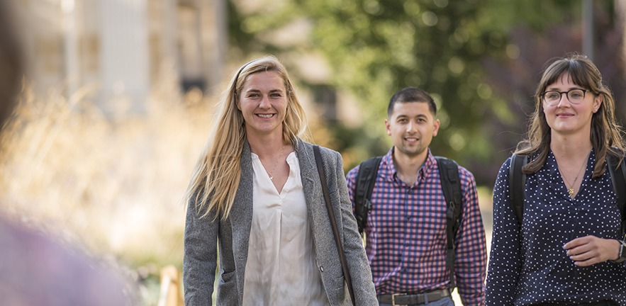Three Cambridge MBA students strolling through Cambridge with smiles on their faces.