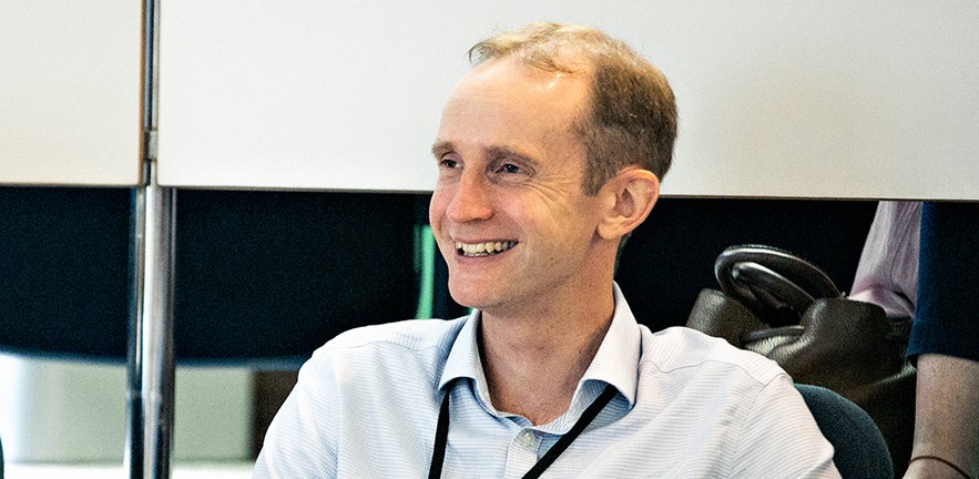 A male delegate smiles at what the speaker is saying.