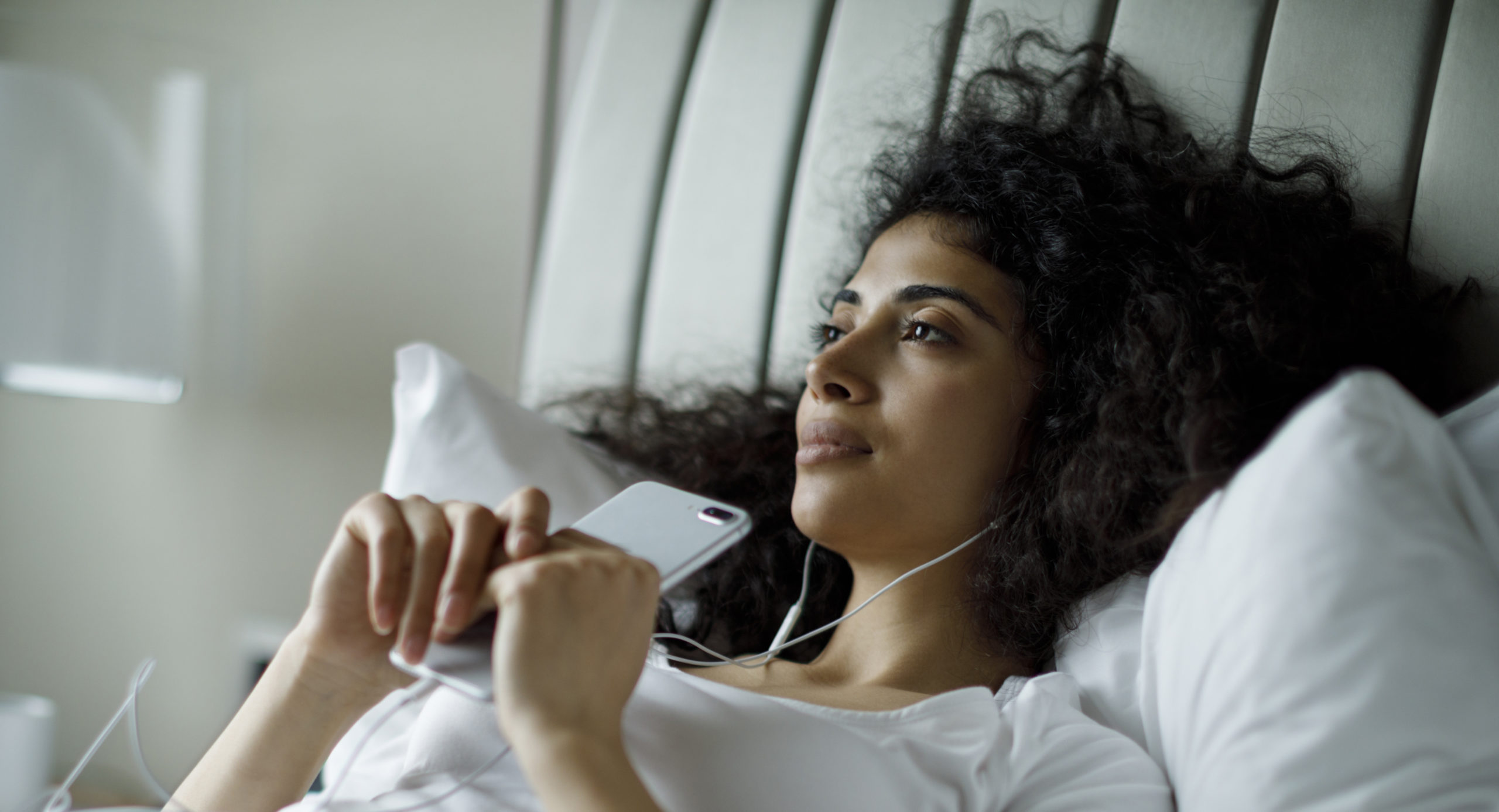 Woman looking thoughtful as she listens to an app on her phone.