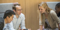 MBA students sit in groups discussing their work.