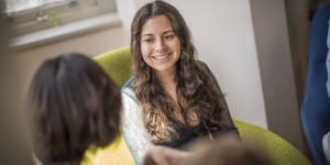 A smiling female MBA student talks to a peer in the Cambridge Judge Business School Common room.