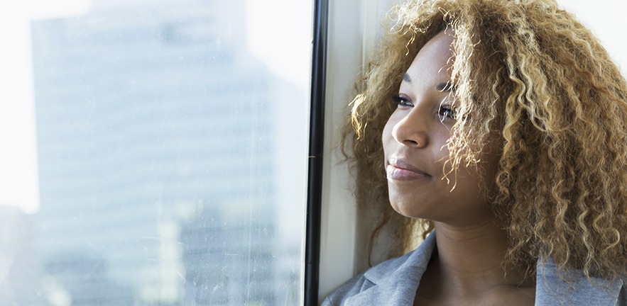 Woman with a slight smile on her face gazing out of a window.