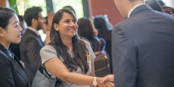 A smiling MBA student shakes the hand of another student upon meeting during Orientation week.