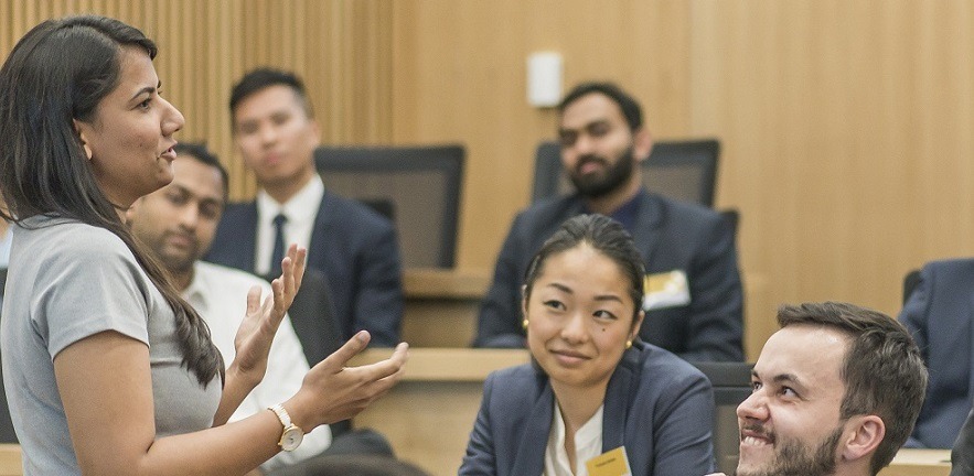MBA student speaking to other MBA students in class during a project session.