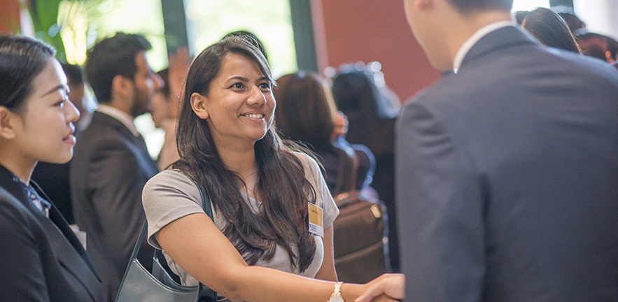 Srishti smiling as she shakes hands with a fellow student.