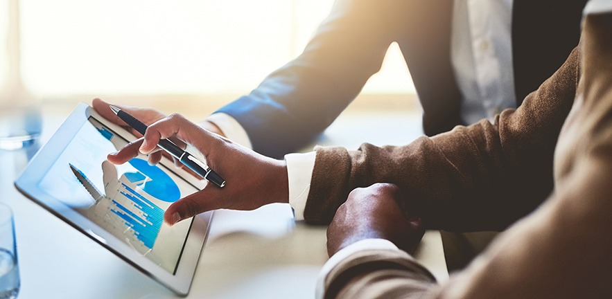 Closeup shot of two unidentifiable businessmen working together on a digital tablet in an office.