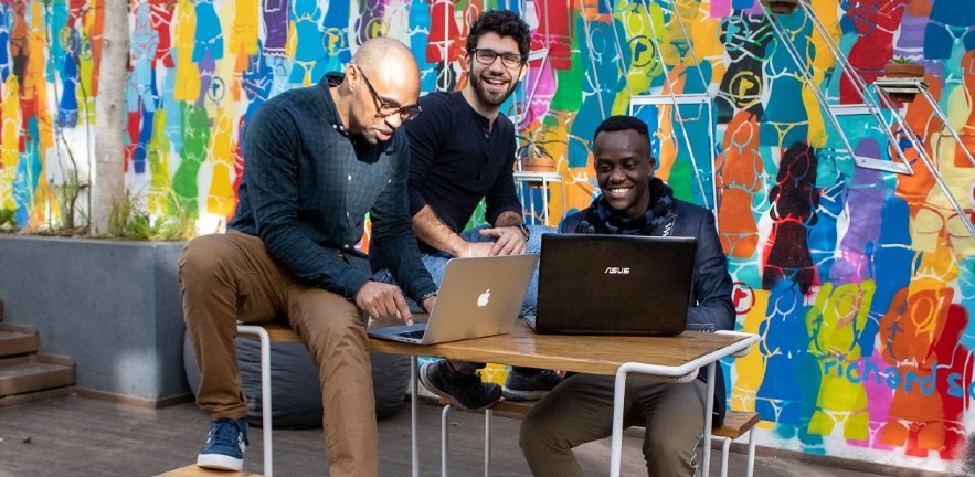 Three people enjoying a HyperionDev coding bootcamp.