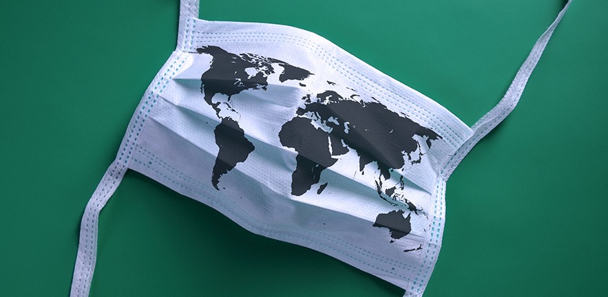 White face mask with a map of the world lying on a green background.