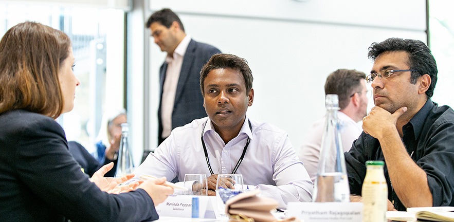 Image of two men and a woman engaged in conversation in a classroom.