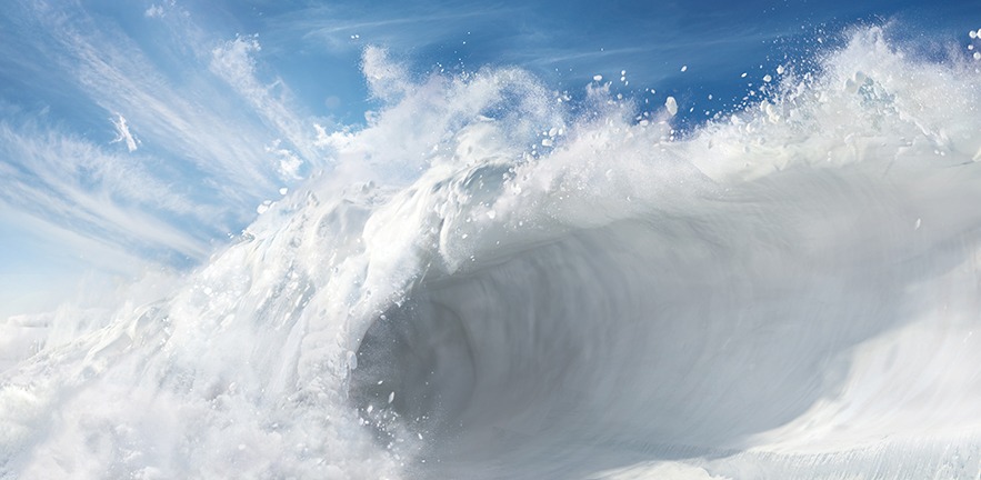 Rolling wave of snow against a bright blue sky.