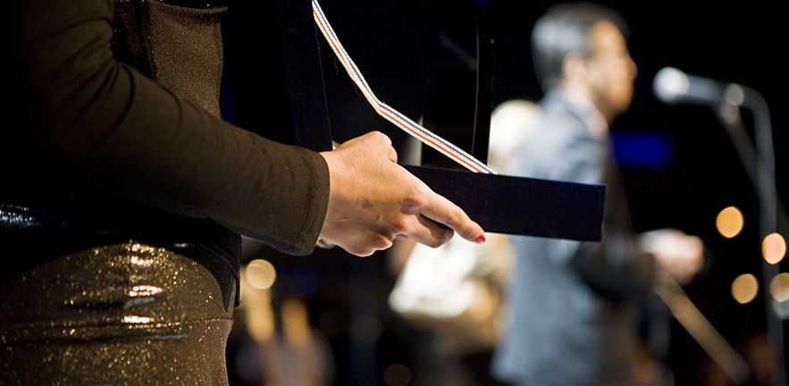 Woman holding an award at an awards ceremony.