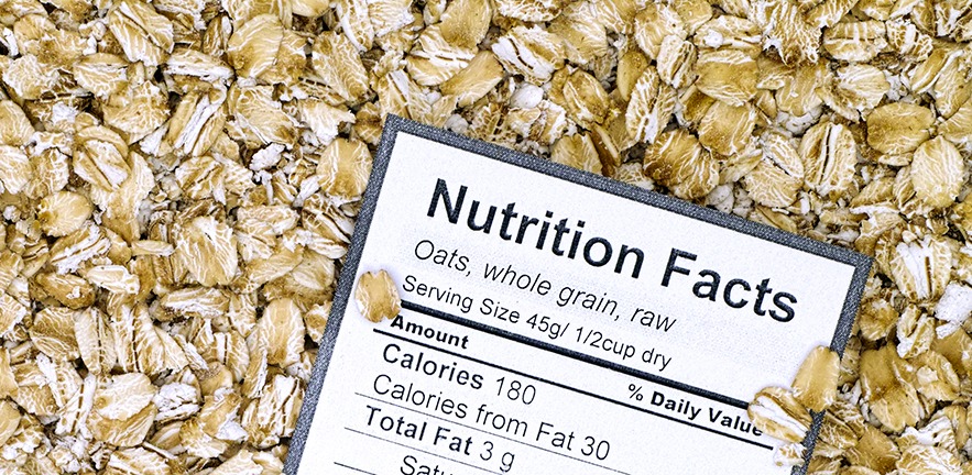 Nutrition facts of whole grain raw oats with oat flakes background.
