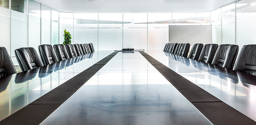 Very long board table in a uniform and symetrical board room.