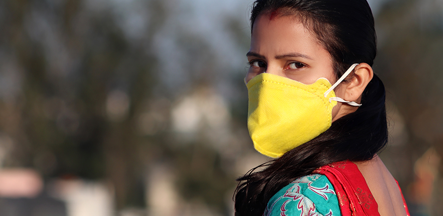 Young Indian women wearing pollution mask against Coronavirus or COVID-19 and standing on rooftop at home in Delhi, India.