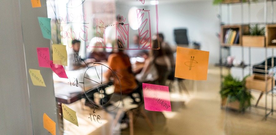 Shot through glass of a group of people in a business meeting at a creative office.