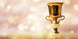 Golden trophy on wooden table, bokeh and glitter background with copy space.
