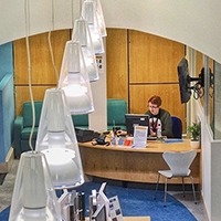 A photo taken from the mezzanine level of the library showing a librarian at the front desk.