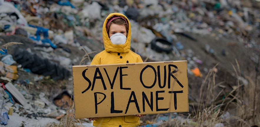 Front view of small child holding placard poster on landfill, environmental pollution concept.