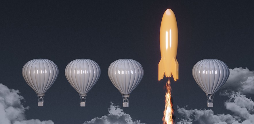 A yellow rocket ship blasts past a row of grey hot air balloons floating in the clouds.