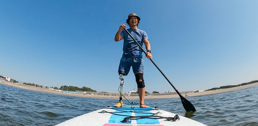 A font view of a man paddle boarding in the sea.