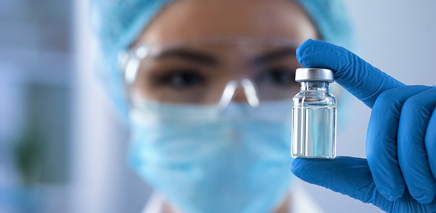 Female scientist looking at ampoule with new medication, vaccination development.