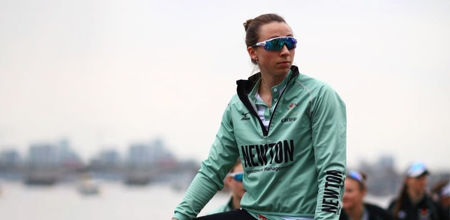 Olivia Coffey focussed while preparing for a race, one foot in the rowing boat.