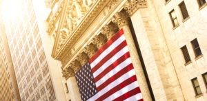 The New York Stock Exchange on Wall St, overlaid with the American flag.