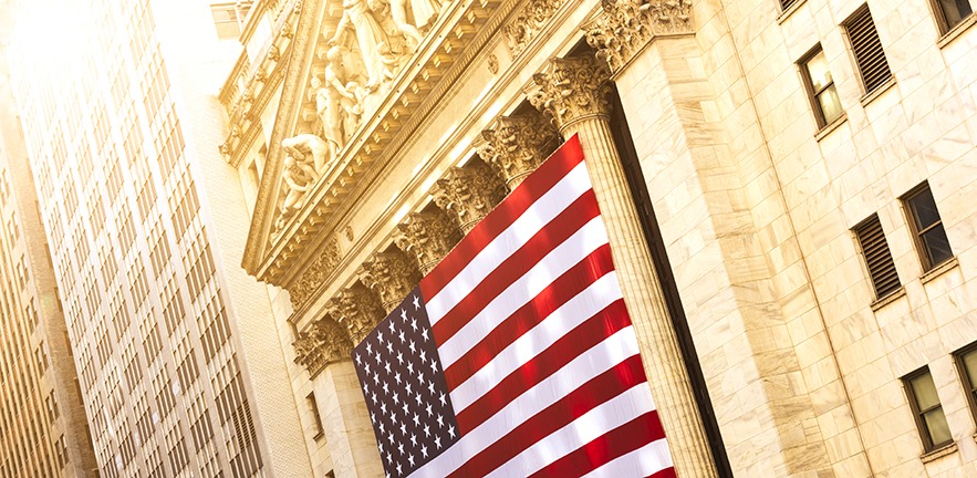 The New York Stock Exchange on Wall St, overlaid with the American flag.