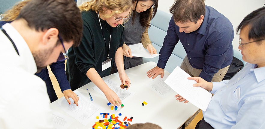 A group of men and women engaged in a teamwork task using building blocks.